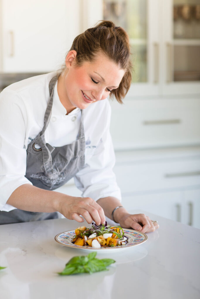 Haley_113 Chef garnishes a colorful dish with fresh herbs in a modern kitchen.